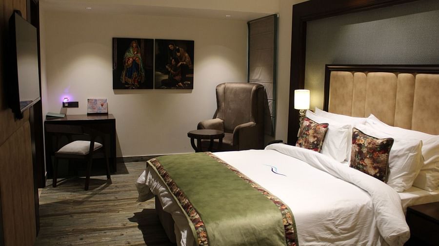 Side view of a bedroom featuring a working table, a chair, and portraits adorning the wall at BluSalzz Residence, Amritsar